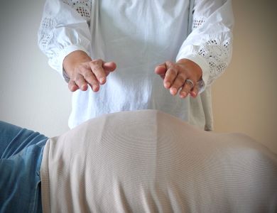Anitha geeft reiki met haar handen boven de buik en rug